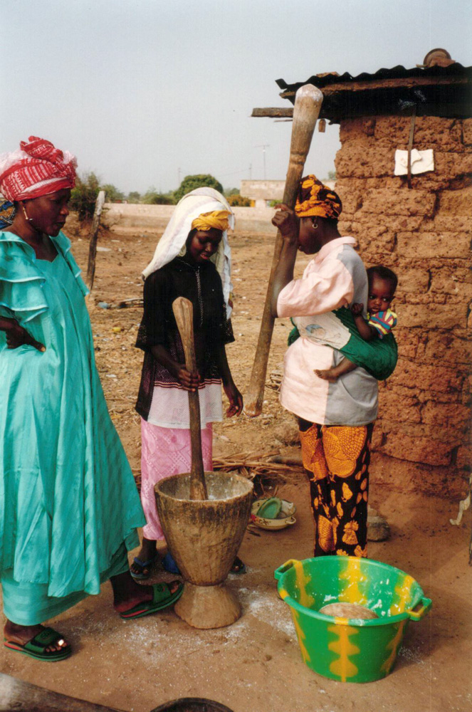 Women pounding maize in wooden mortar